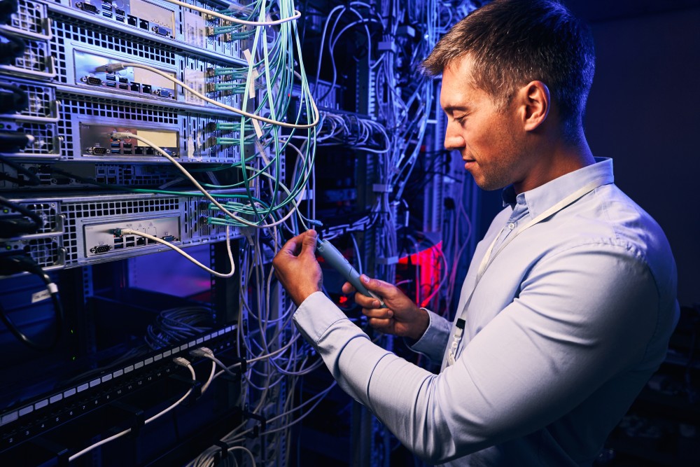 Technician installing fiber optic cable in a data center Technician installing fiber optic cable in a data center