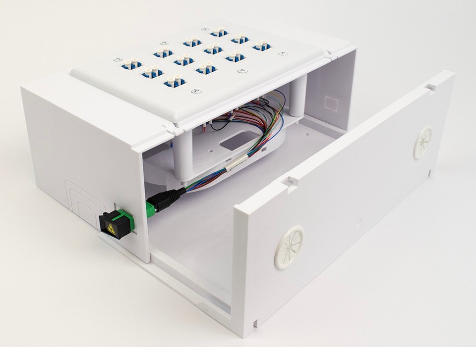 Wall-mounted FTTD enclosure showing organized internal fiber cable routing and connections.