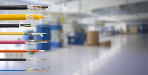 An organized display of various fiber optic cable jackets in different colors (aqua, yellow, orange, and lime green), representing the choice between OM3, OM4, OS2, and OM5 standards.