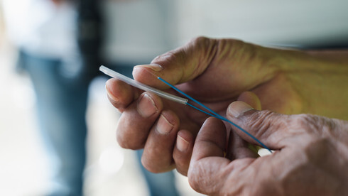 A technician using a Visual Fault Locator (VFL) to send a red laser light through a fiber strand, identifying the exact location of a break or leak in the cabling.