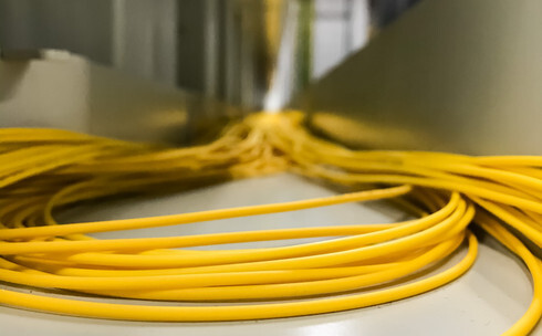 A side-view of a fiber optic cable being coiled, showing the specific curve of its bend radius to illustrate how to maintain cable integrity and prevent glass breakage.